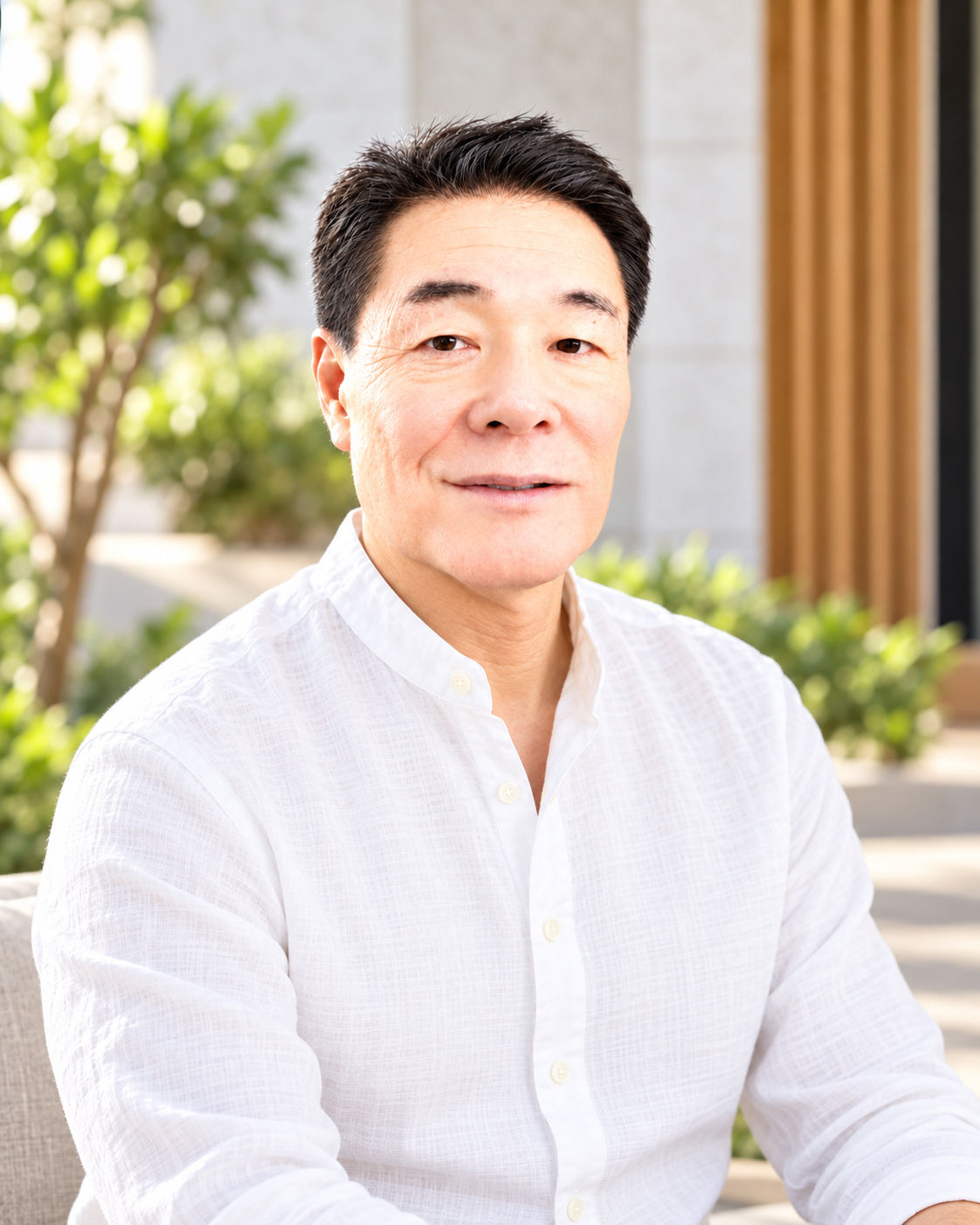 Eiji Takamori in a white shirt, photographed in a softly lit garden courtyard